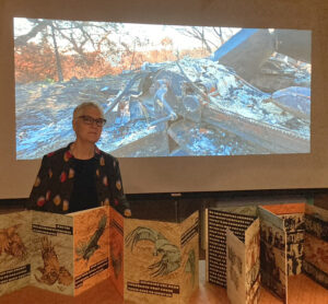 Woman standing before projected image with artists' book