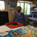 woman with artists' book open to her painting