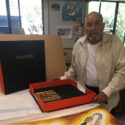 man with artists' book open to his painting