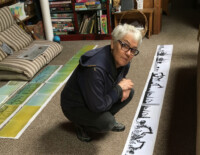 woman crouched over layout of artists' book on floor